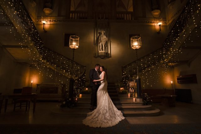 A Bride and Groom embrace on the staircase at Ashridge House